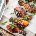 Slow Cooker Sticky Chicken Drumsticks on cookie sheet topped with sesame seeds