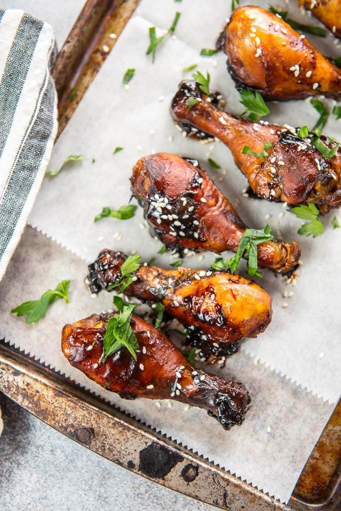 slow cooker chicken drumsticks on cookie sheet with sesame seeds and cilantro