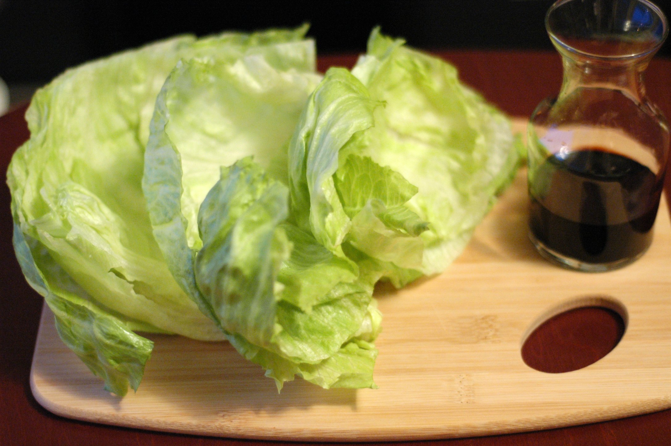 Head of lettuce on cutting board with cruet of soy sauce 