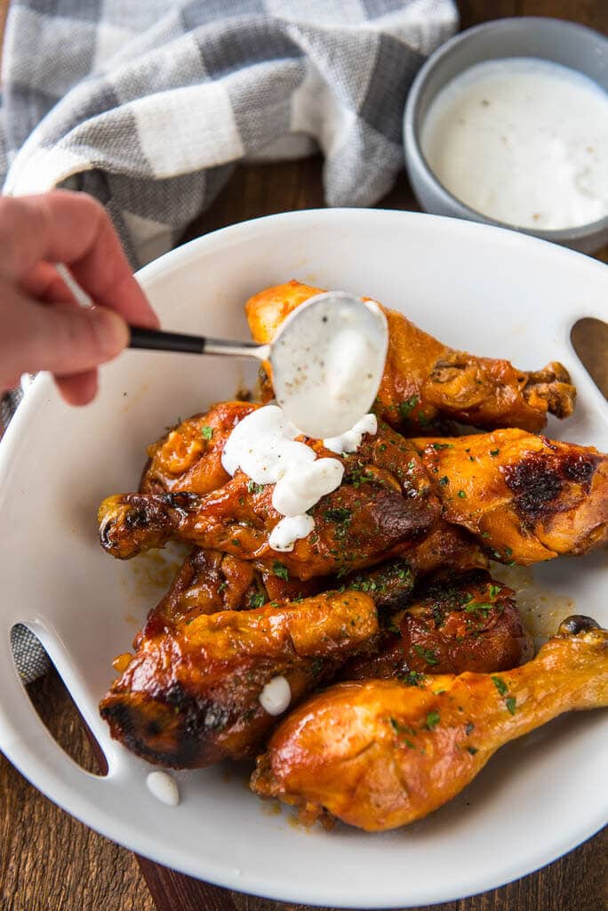 Slow Cooker Buffalo Chicken Drumsticks while drizzling with blue cheese dressing