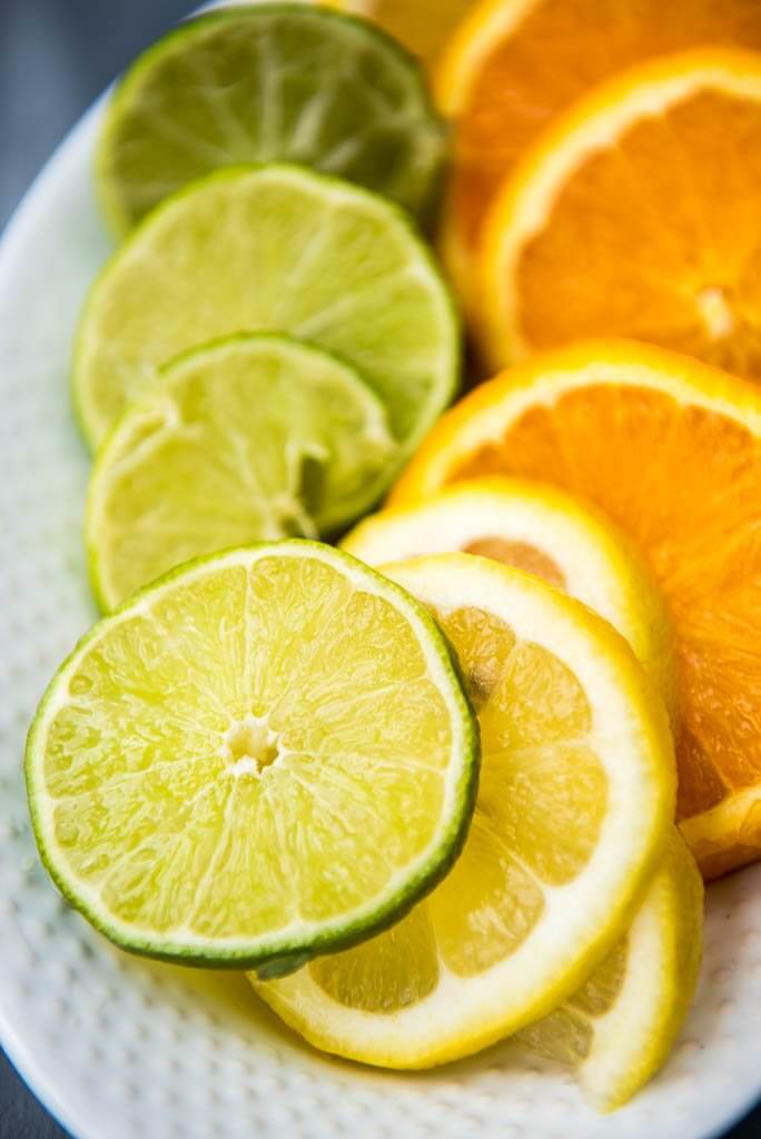 Close up shot of lemon and lime slices on a white platter.