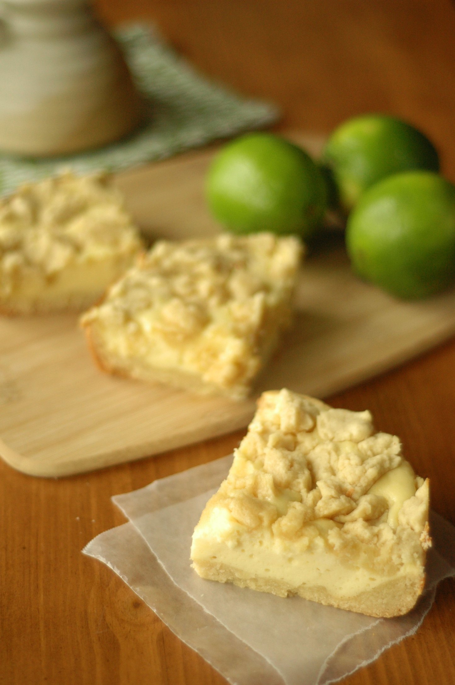 Cheesecake Cookie Bar on wax paper with two bars and three limes on cutting board in background