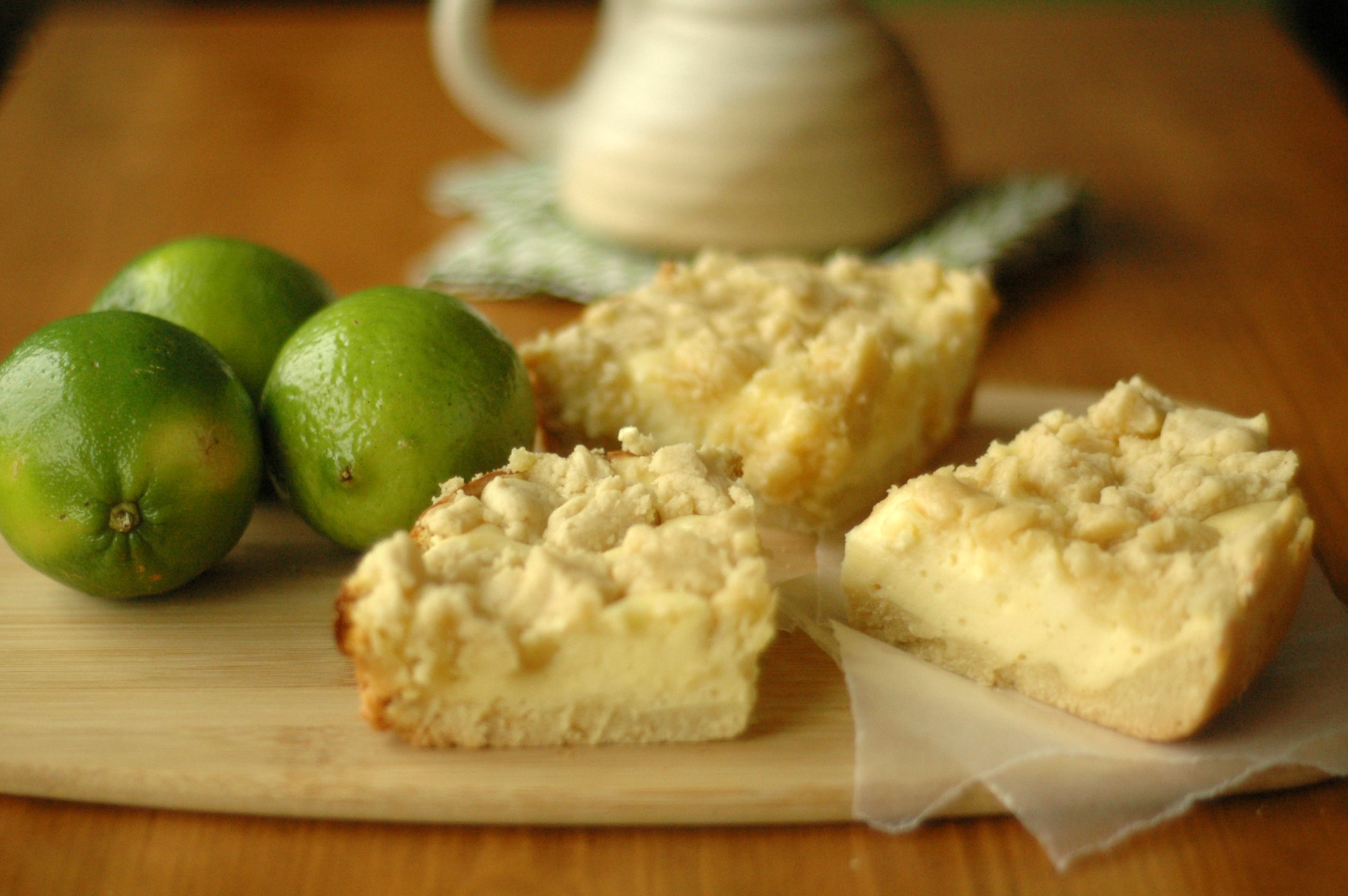 Cheesecake Cookie Bars on cutting board with three whole limes