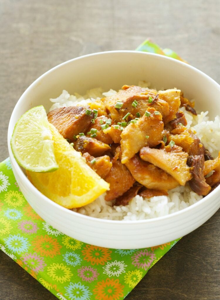 Slow Cooker Honey Crispy Chicken with white rice and lemon/lime wedges in white bowl