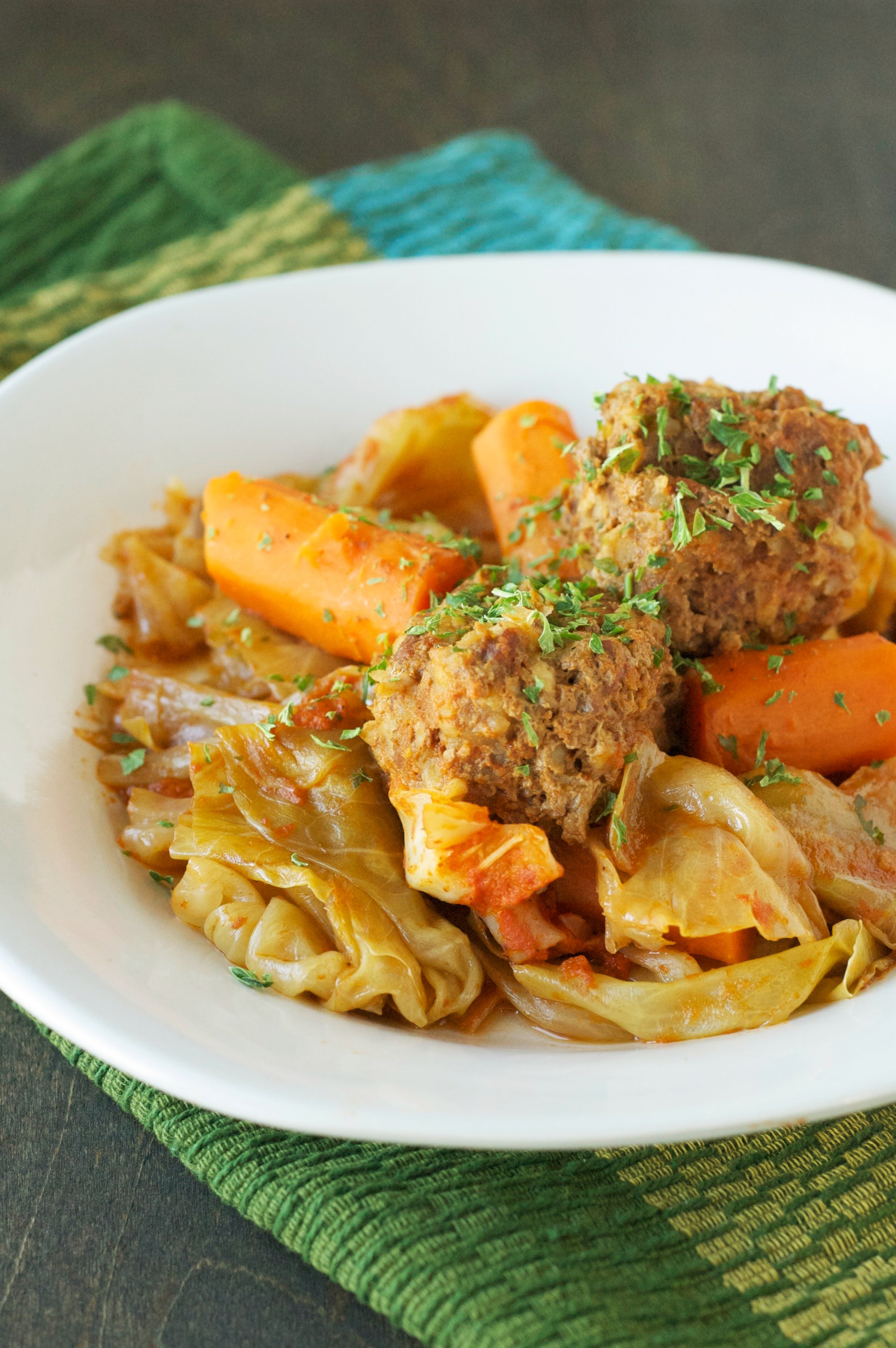 meatballs, carrots and cabbage in white serving plate on blue and green placemat