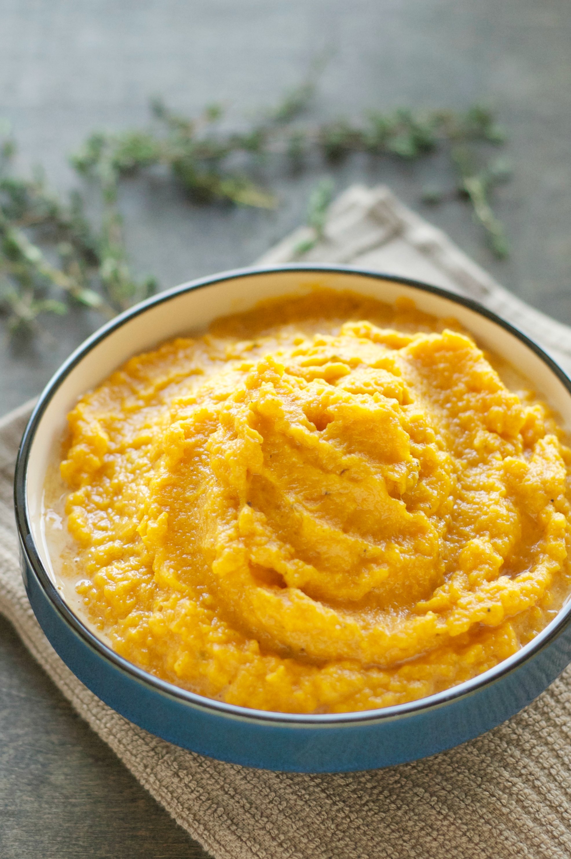 blue bowl of mashed sweet potatoes on brown towel