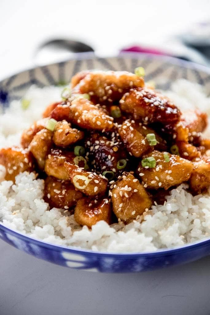 honey crispy chicken over white rice in a blue and white bowl