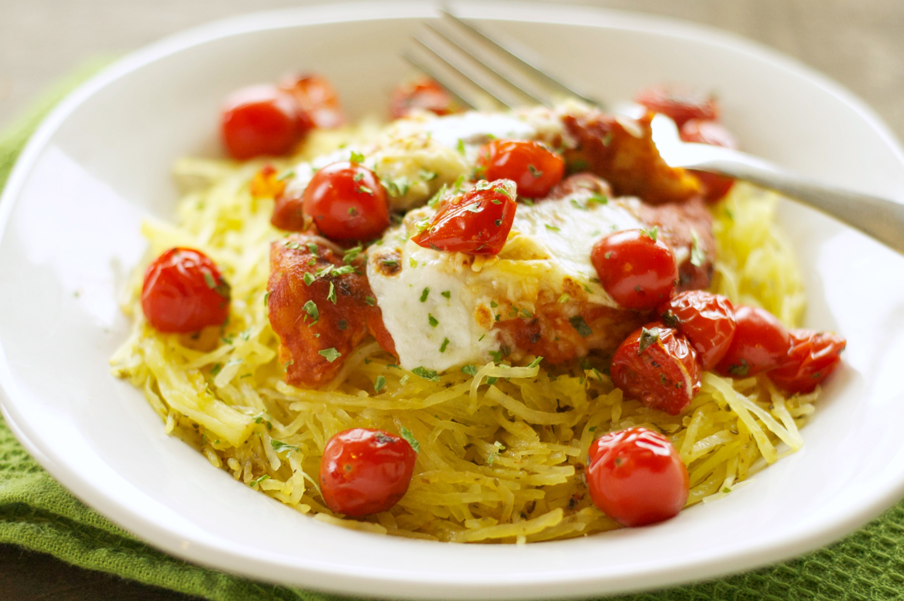white bowl with chicken, tomatoes on bed of spaghetti squash