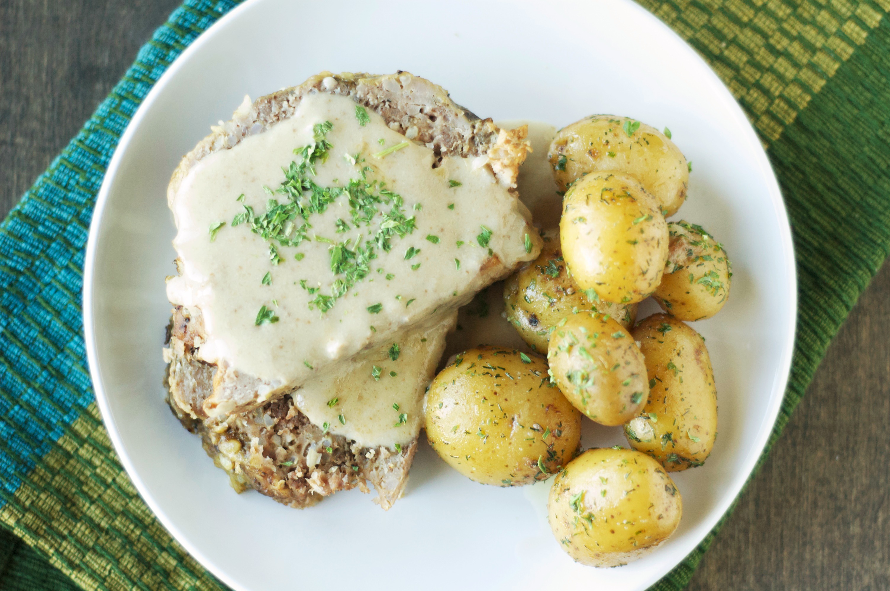 Top view of Slow Cooker Creamy Meatloaf with Baby Dill Potatoes on white plate