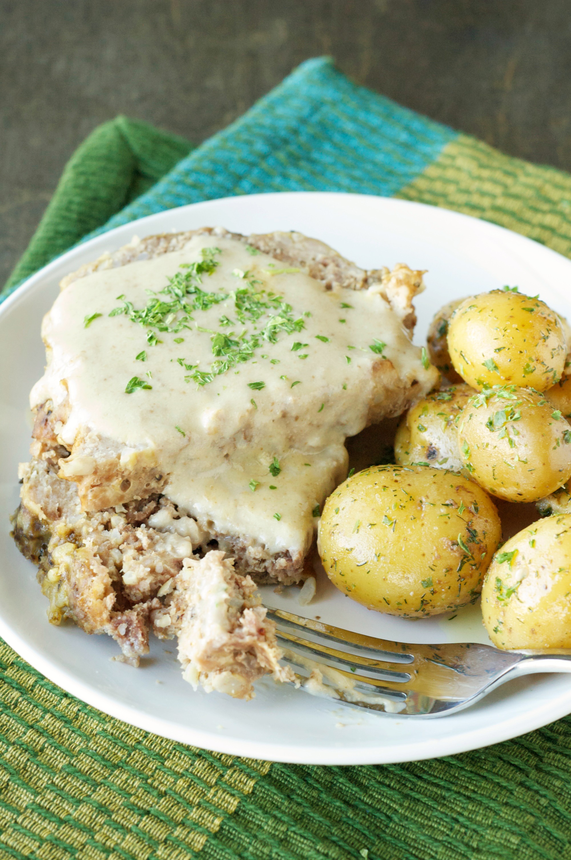 Top view of Slow Cooker Creamy Meatloaf with Baby Dill Potatoes on white plate with fork