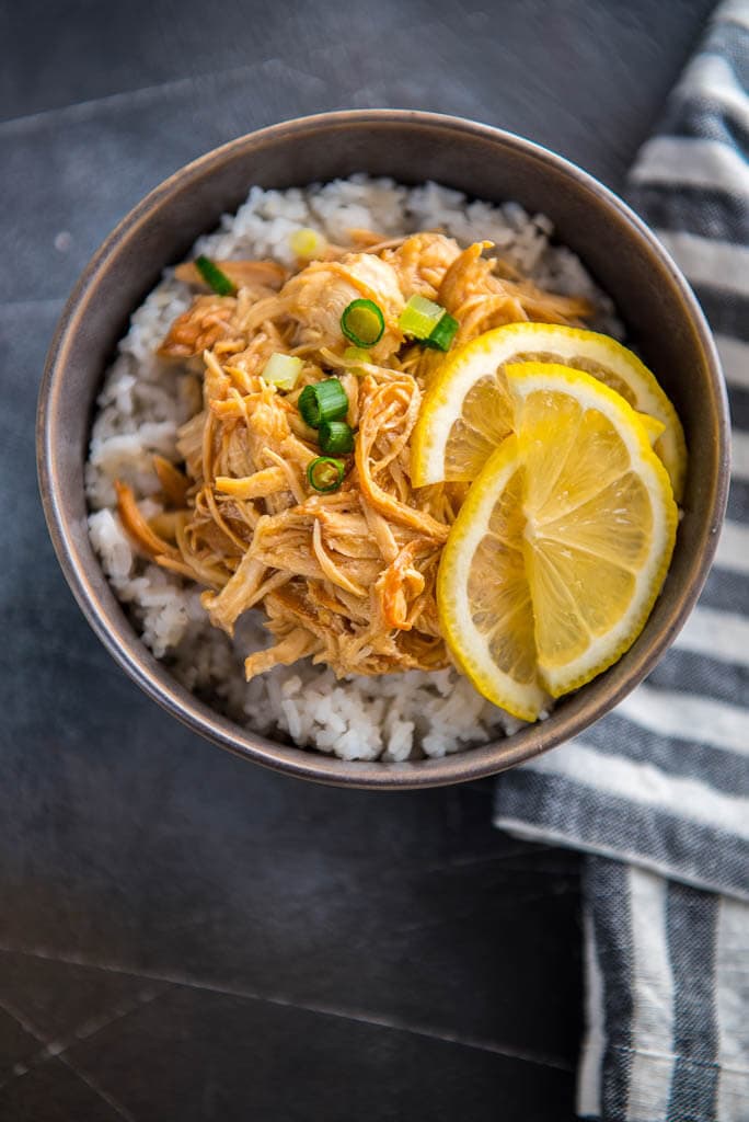 Slow Cooker Lemon Chicken in with lemon slices in gray bowl with rice