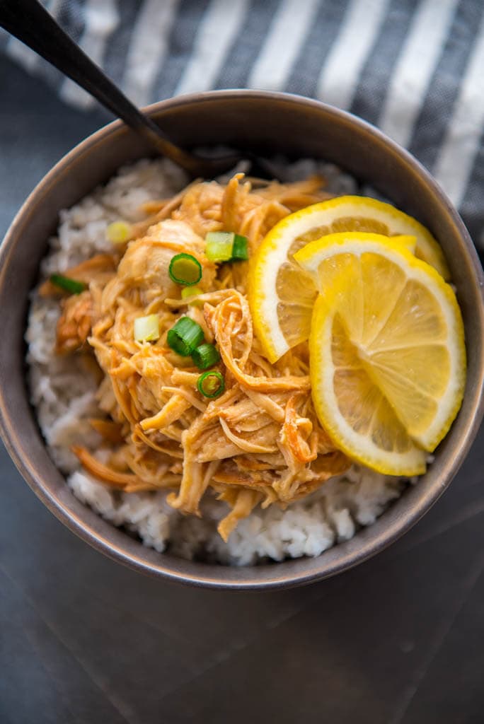 Slow Cooker Lemon Chicken in with lemon slices in gray bowl with rice