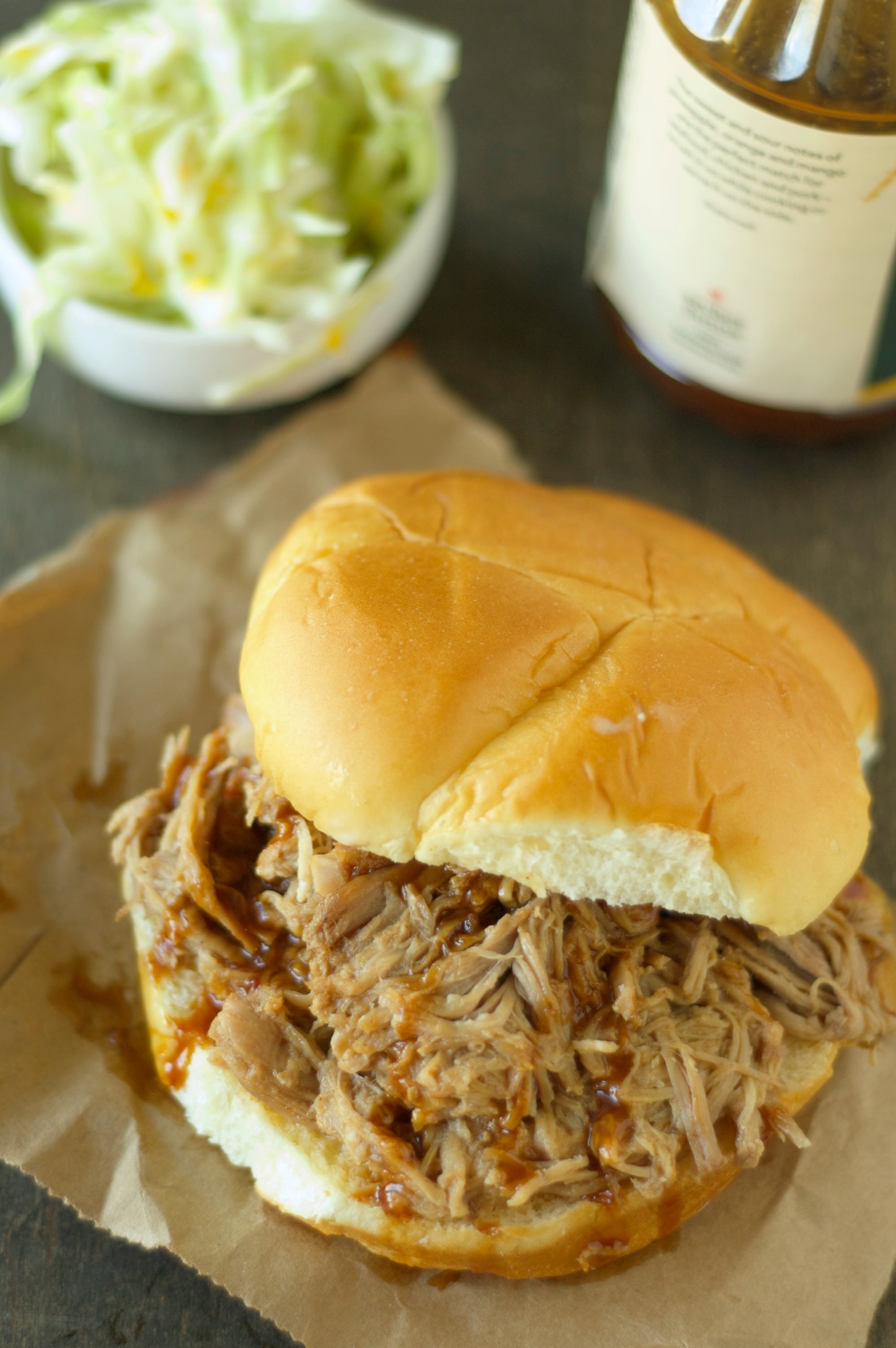 Slow Cooker Pulled Pork on bun with bowl of slaw in background