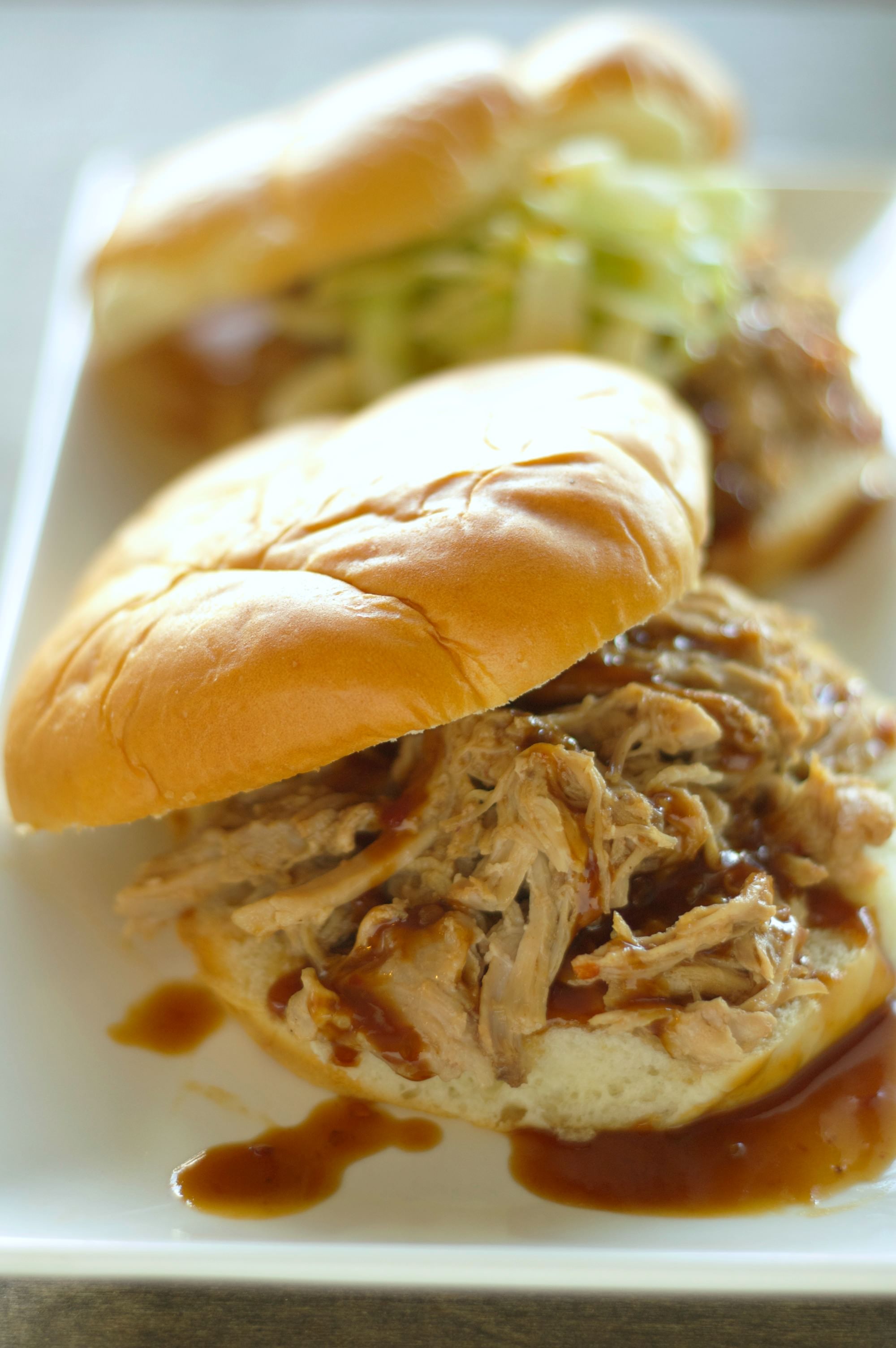 Two Slow Cooker Pulled Pork Sandwiches on buns on a white plate