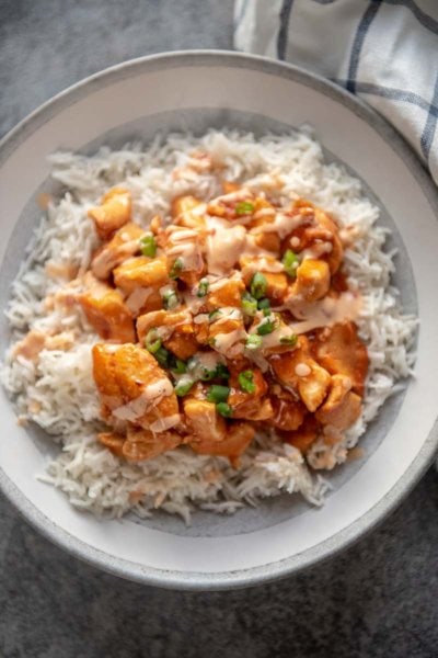 rice topped with honey sriracha chicken in bowl