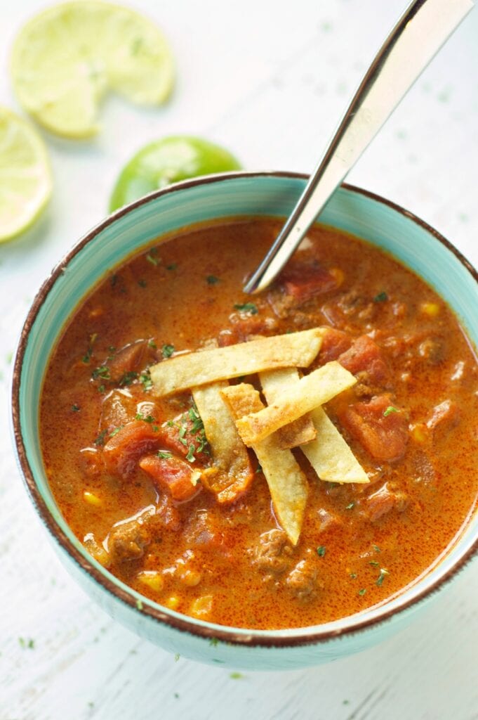 Slow Cooker Beef Enchilada Soup in green bowl with lime slices