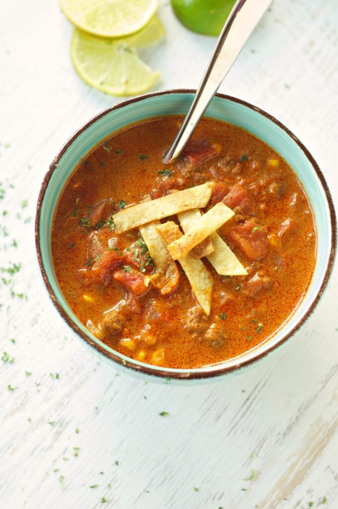 Slow Cooker Beef Enchilada Soup in green bowl with lime slices