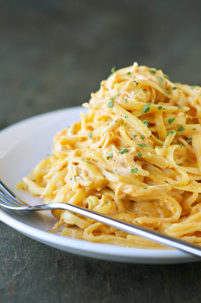 Slow Cooker Cheesy Buffalo Chicken Pasta on a white plate with a fork