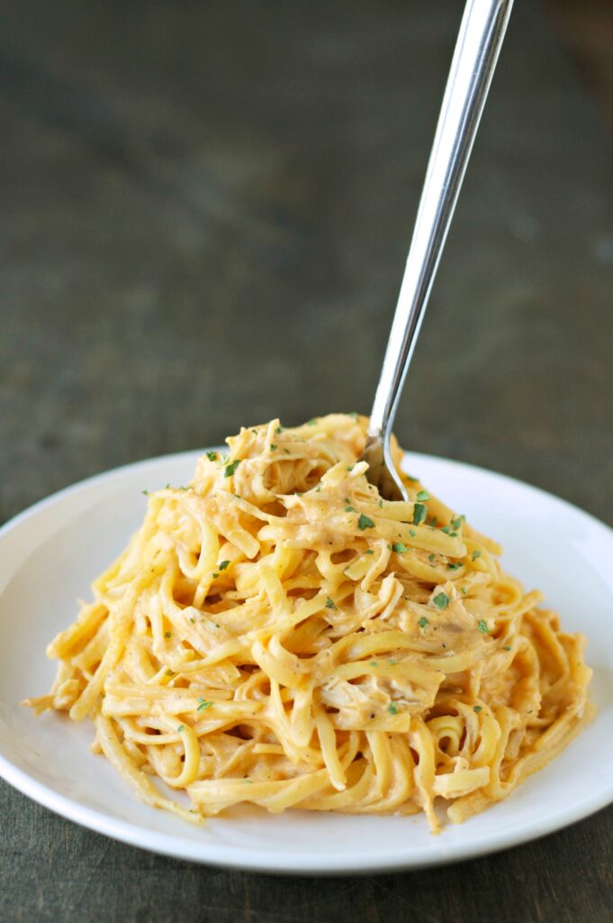 Slow Cooker Cheesy Buffalo Chicken Pasta twirled on a white plate with a fork