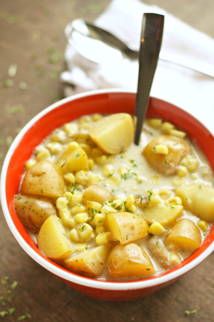 Slow Cooker Corn and Potato Chowder in red bowl with spoon