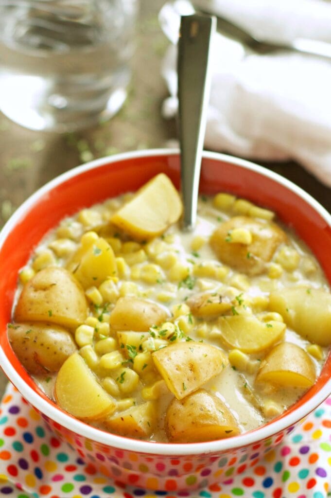 Slow Cooker Corn and Potato Chowder in red bowl with spoon