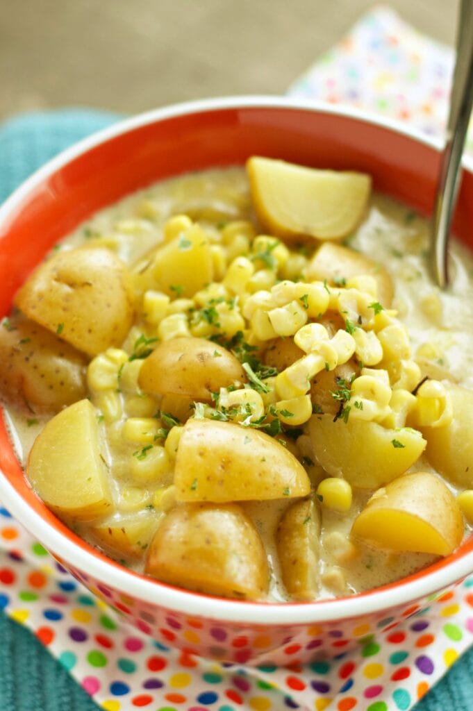 Slow Cooker Corn and Potato Chowder in red bowl with spoon