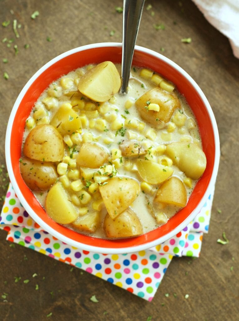 Slow Cooker Corn and Potato Chowder in red bowl with spoon