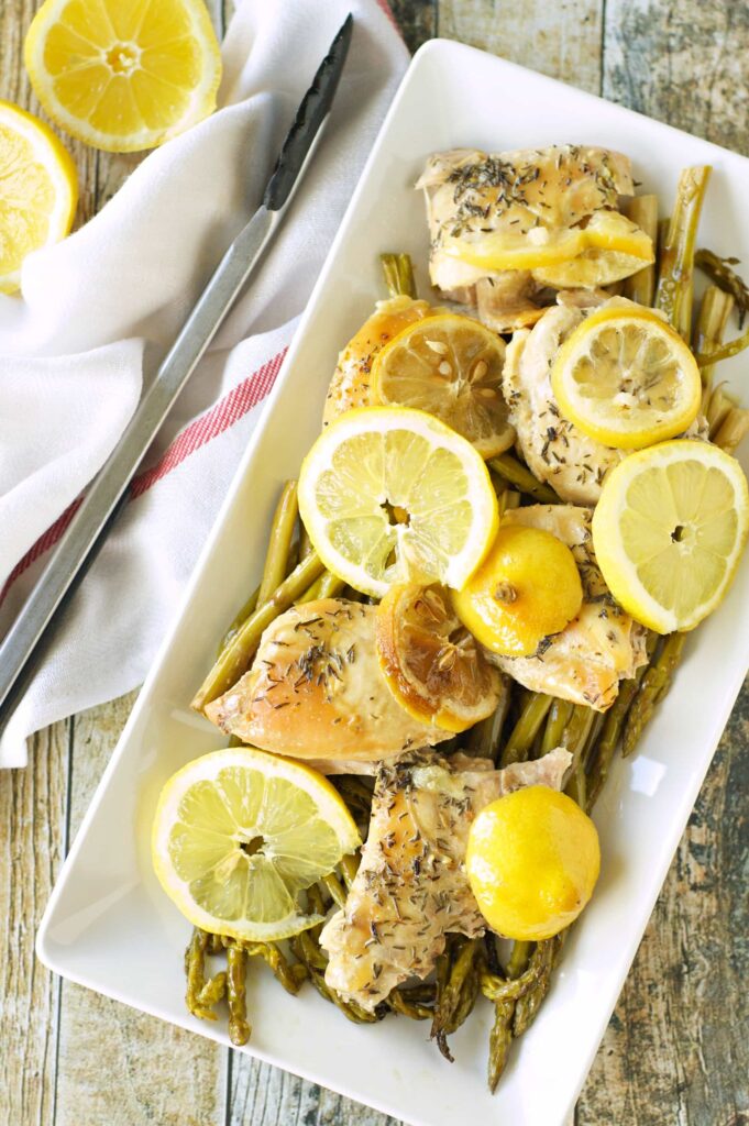 Slow Cooker Lemon Pepper Chicken and Asparagus in white platter with lemon slices