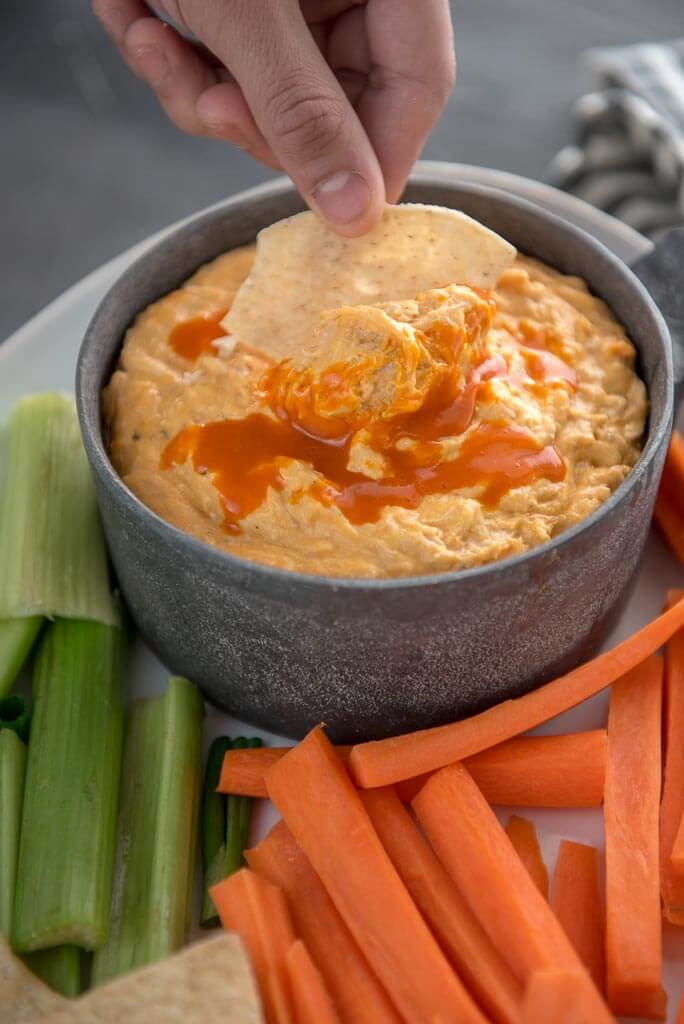 Dipping a chip into Cheesy Slow Cooker Buffalo Chicken Dip
