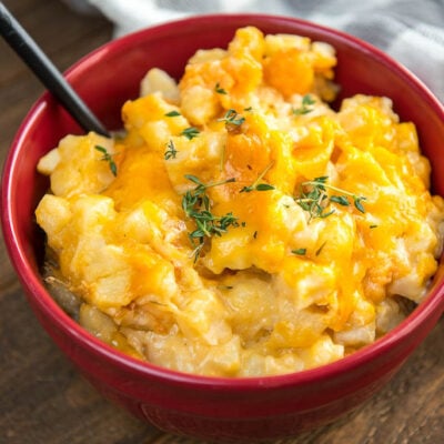Slow Cooker Cheesy Potatoes in a red bowl with a white and gray checkered napkin