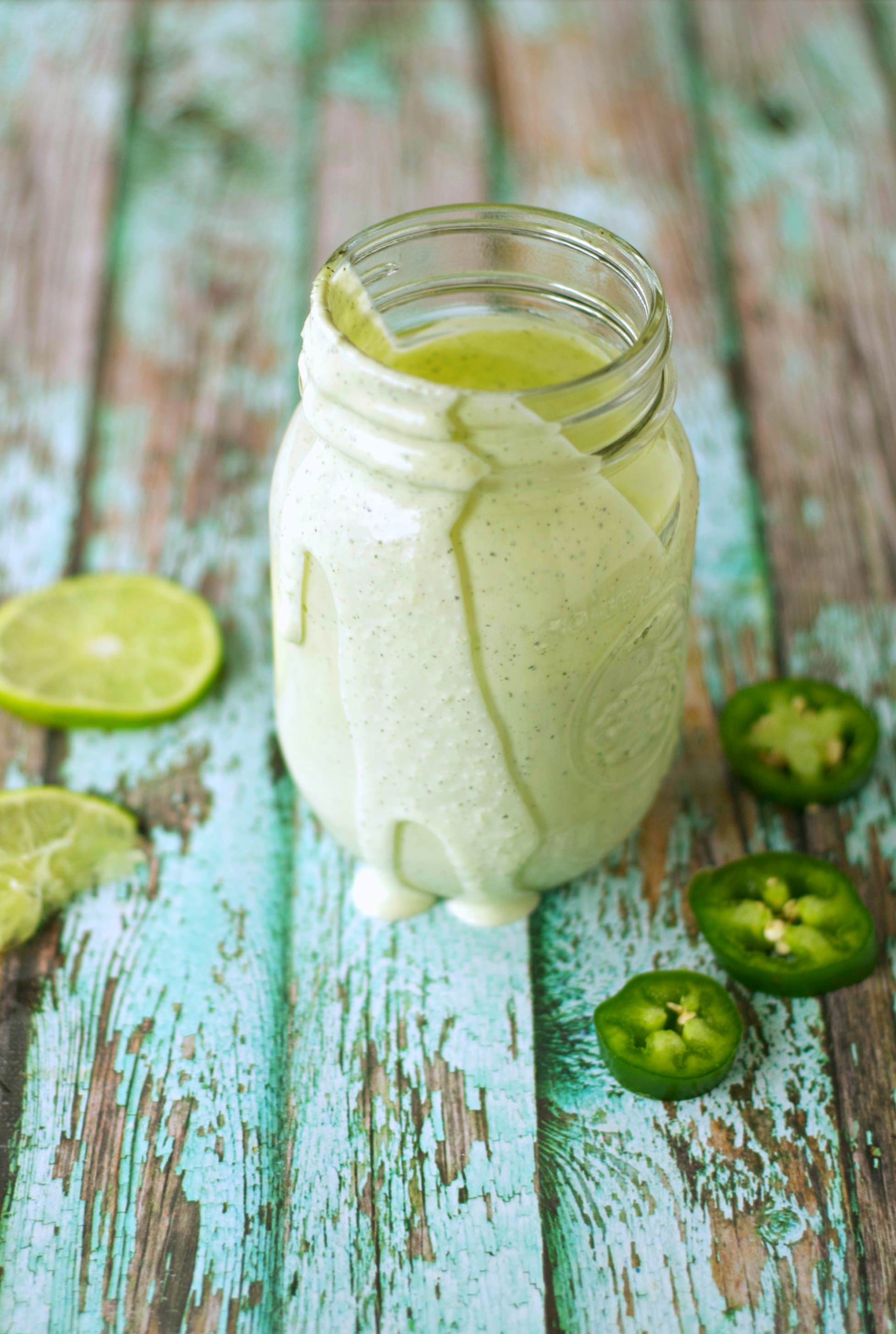 Zesty Lime Jalapeno Ranch in jar with sliced limes and jalapenos on side