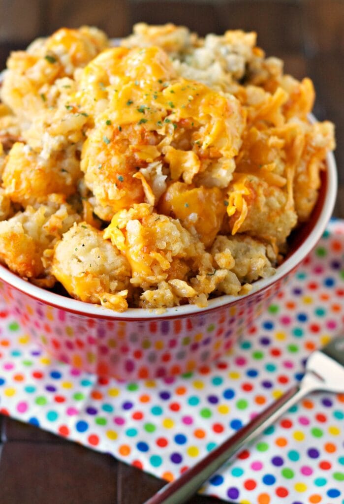 tater tot casserole in red bowl with fork to side