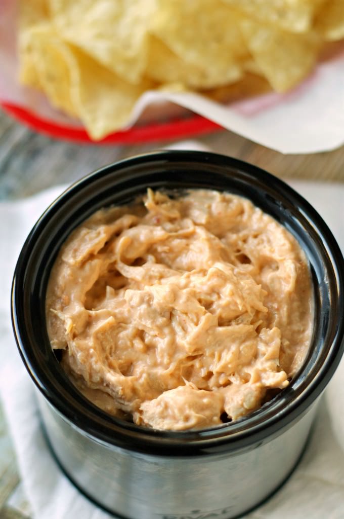 chicken dip in small slow cooker with chip in background