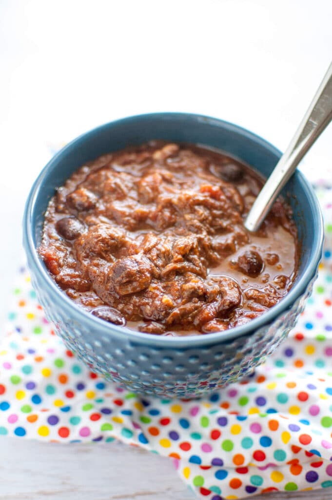 beef short rib chili in blue bowl with spoon