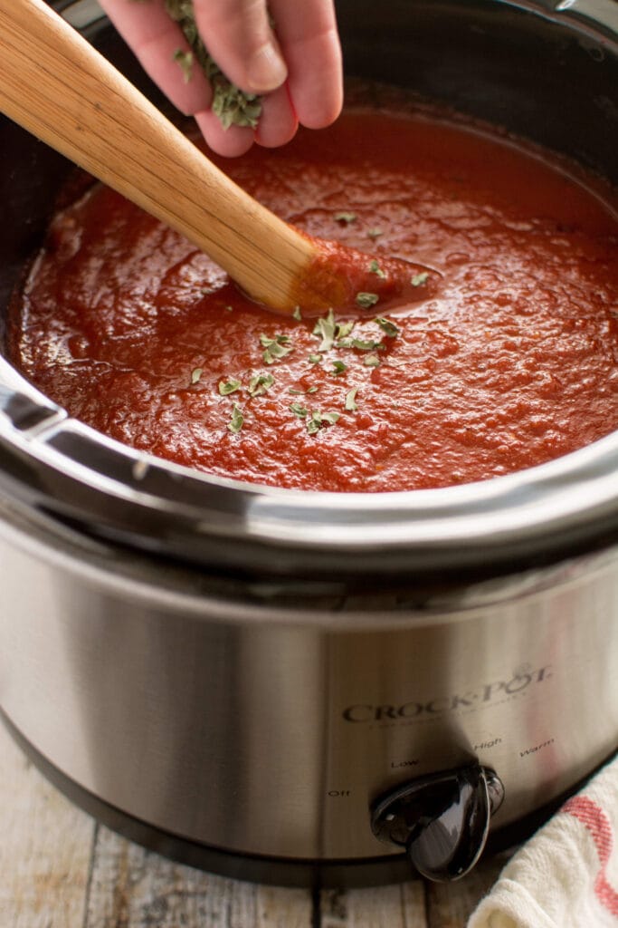 Slow Cooker Roasted Garlic Marinara on wooden spoon and slow cooker 