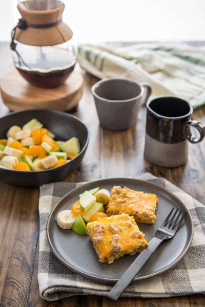 Slow Cooker Easy Breakfast Casserole served on a black plate wtih coffee and fruit.