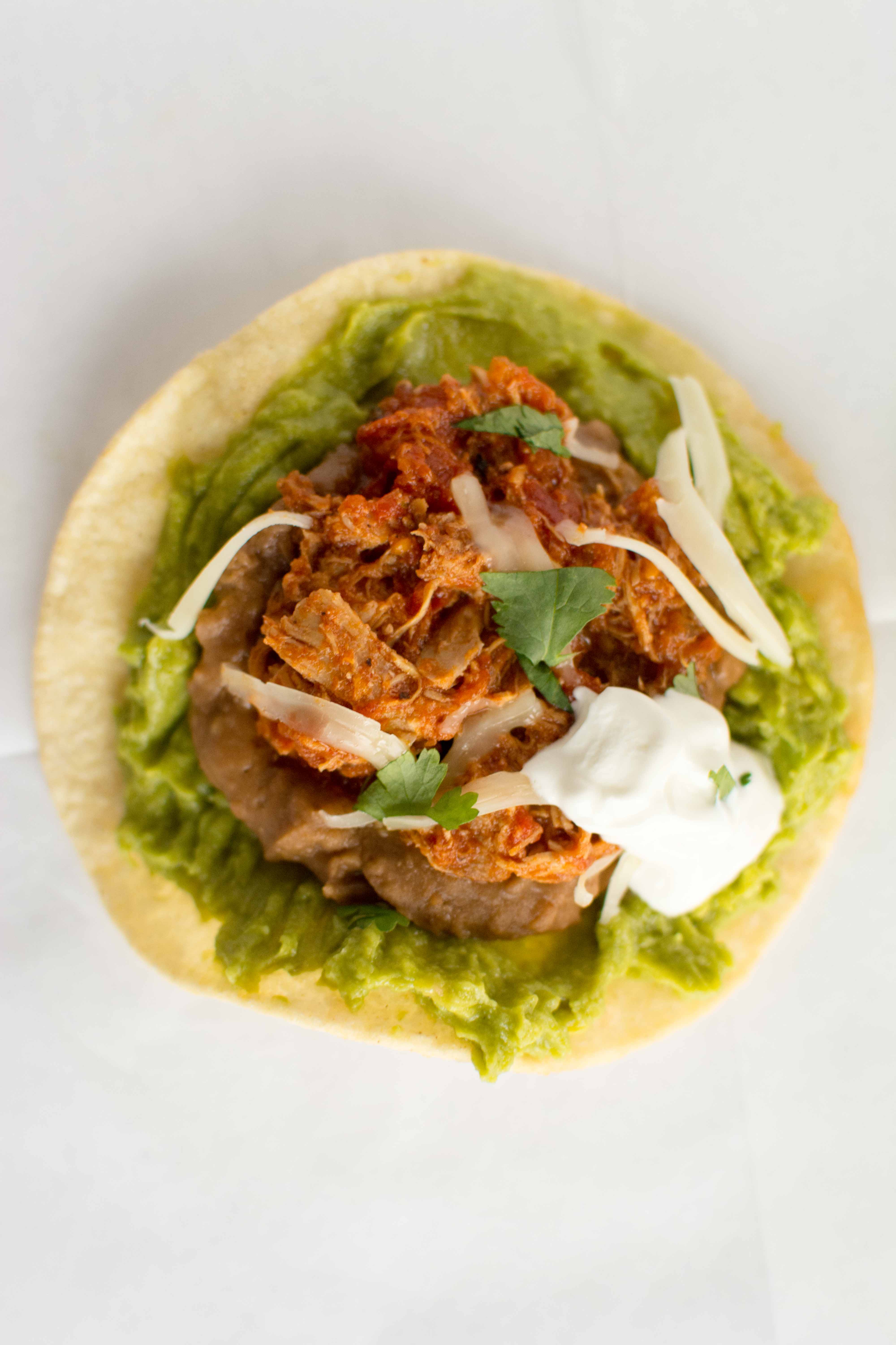 one chicken tinga tostada with dollop of sour cream