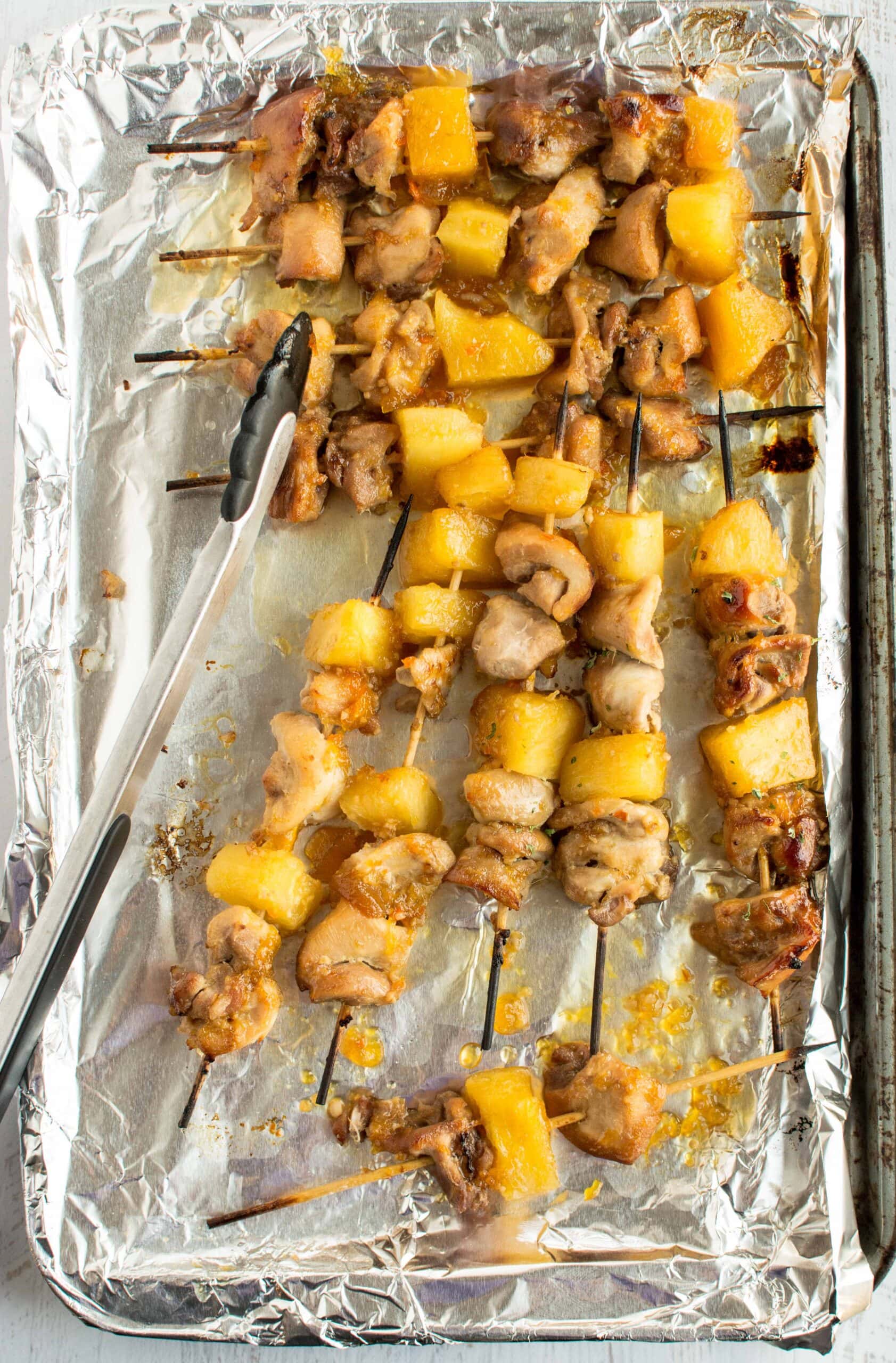 slow cooker chicken skewers on tin foil lined sheet with tongs