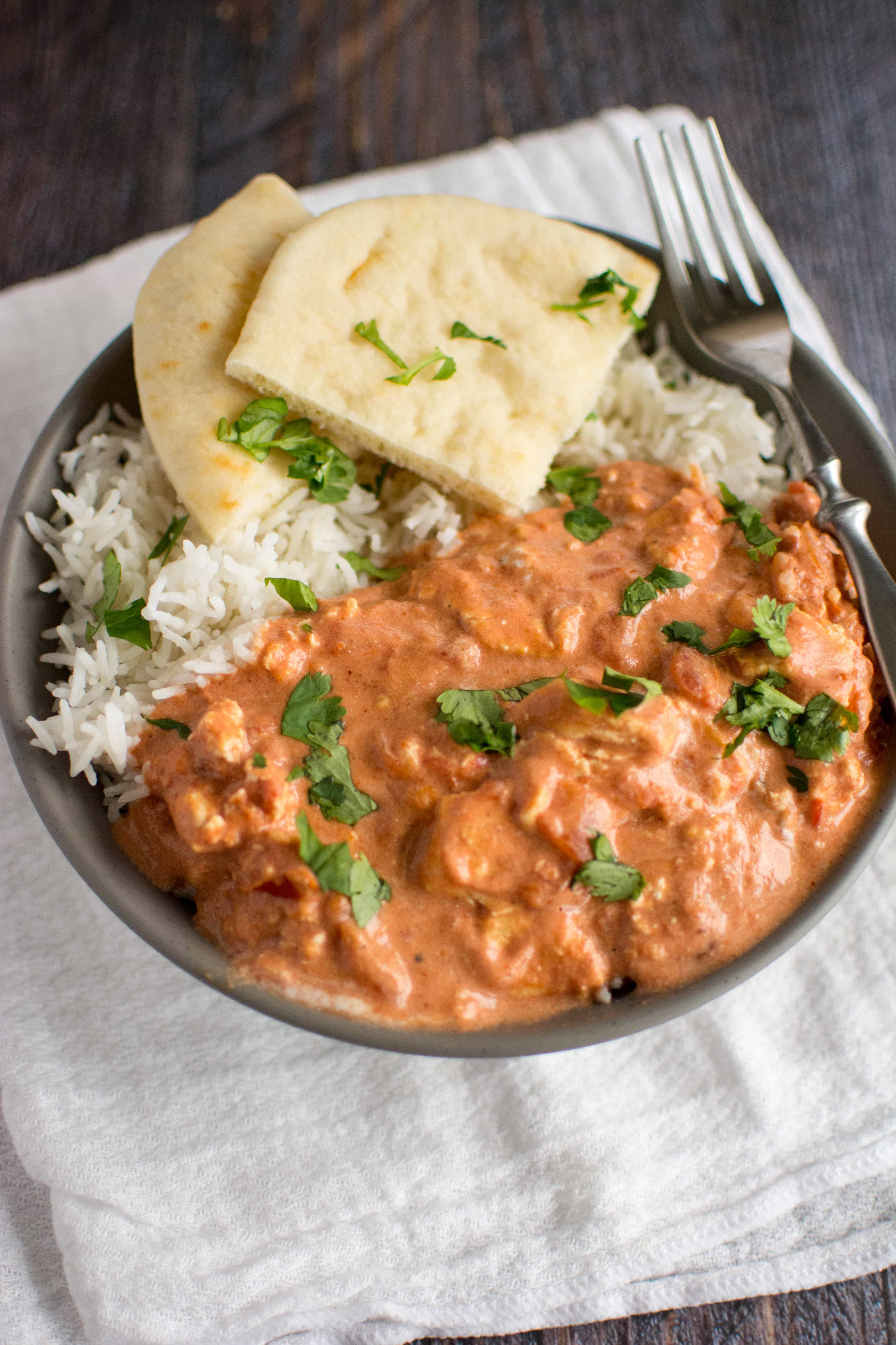 paneer makhani in gray bowl with rice and naan bread with fork on side
