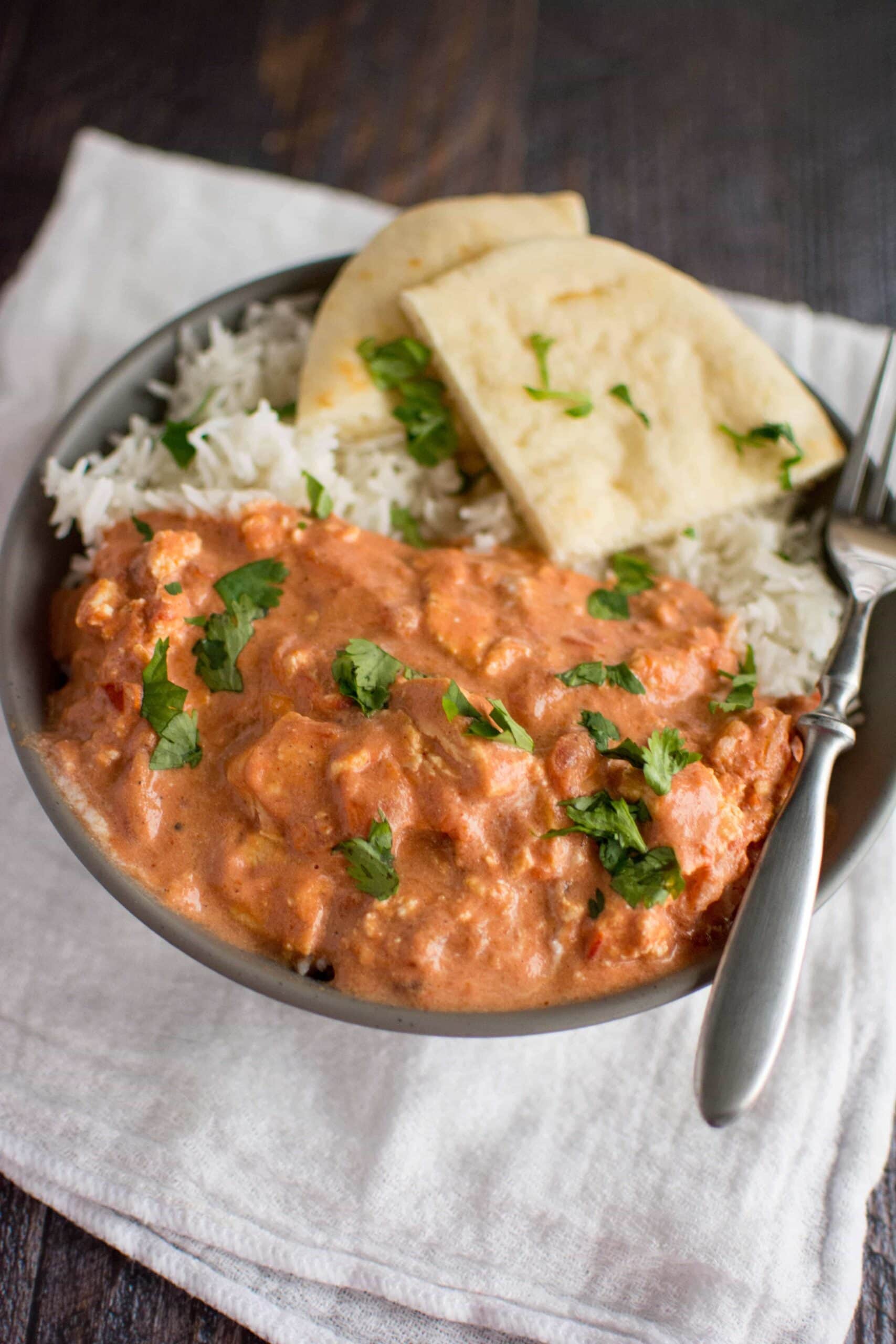 paneer makhani in gray bowl with rice and naan bread with fork on side 
