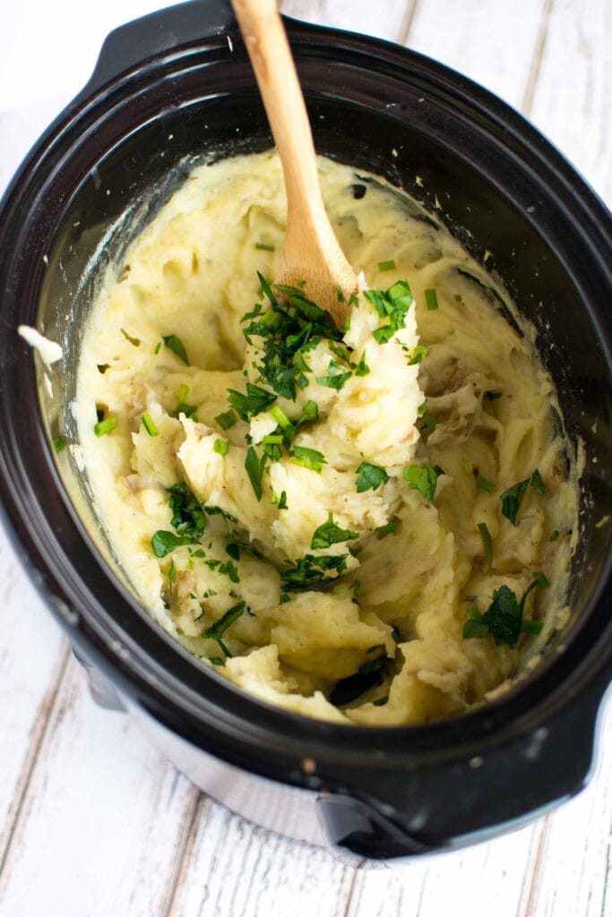 mashed potatoes in slow cooker with wooden spoon