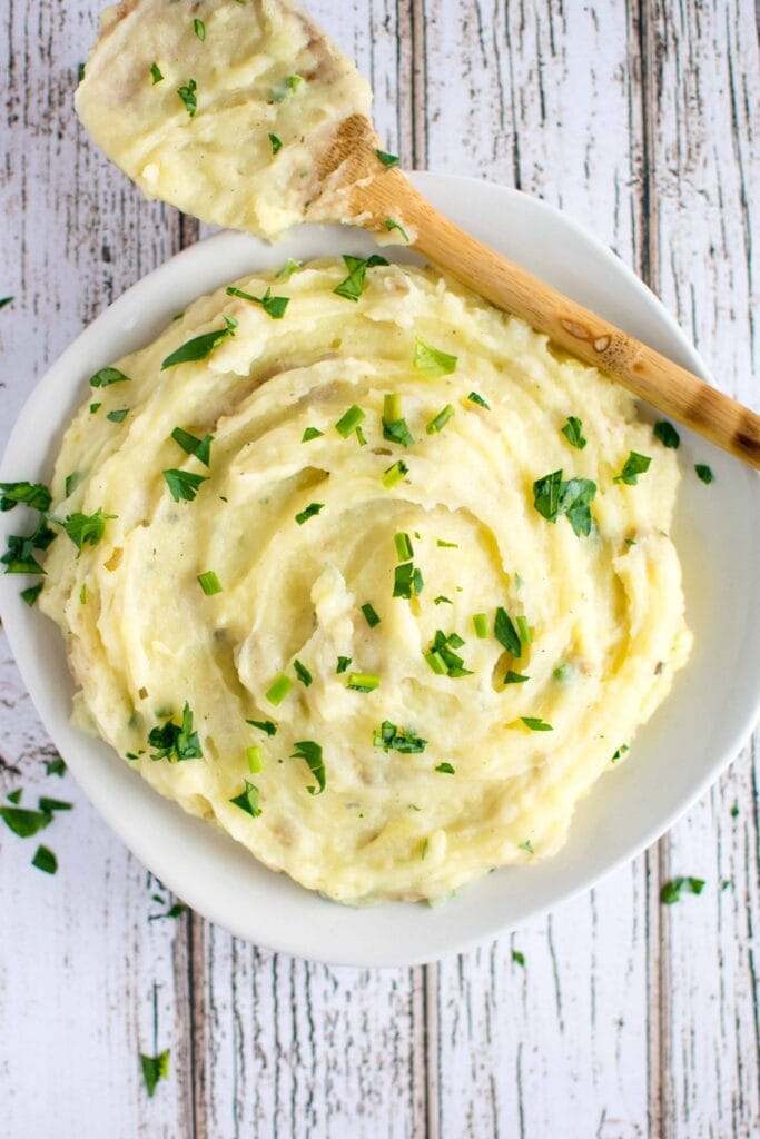 mashed potatoes in white bowl with wooden spoon