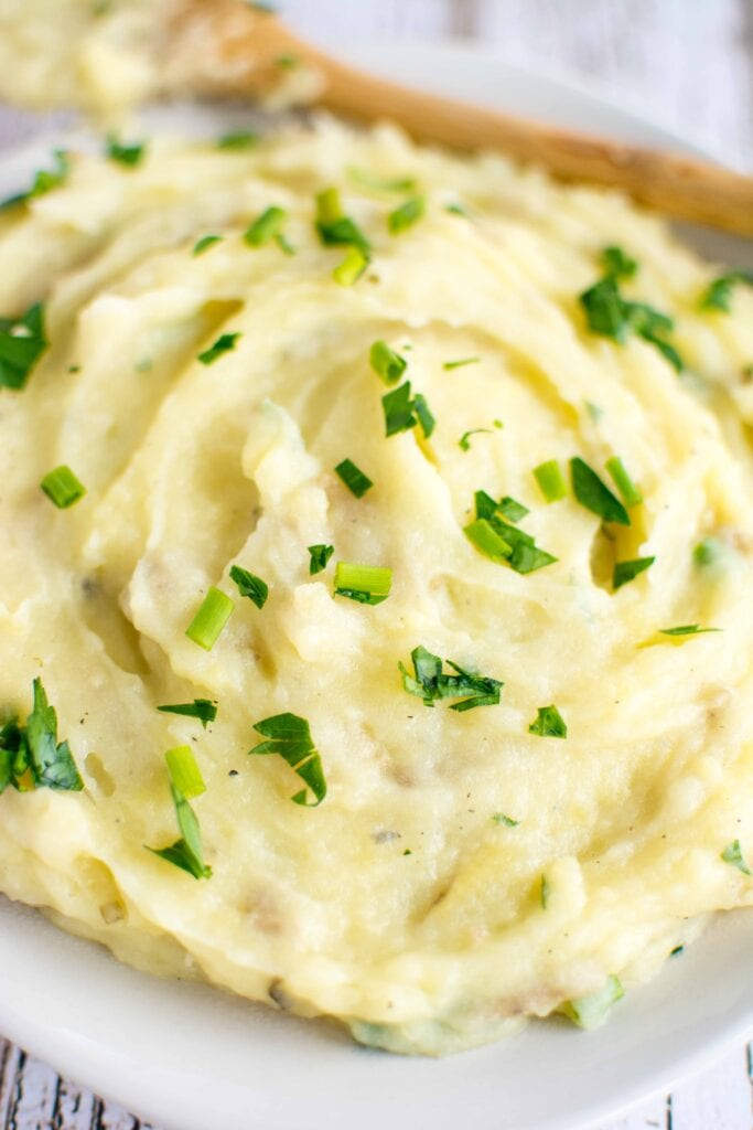 mashed potatoes in white bowl with wooden spoon