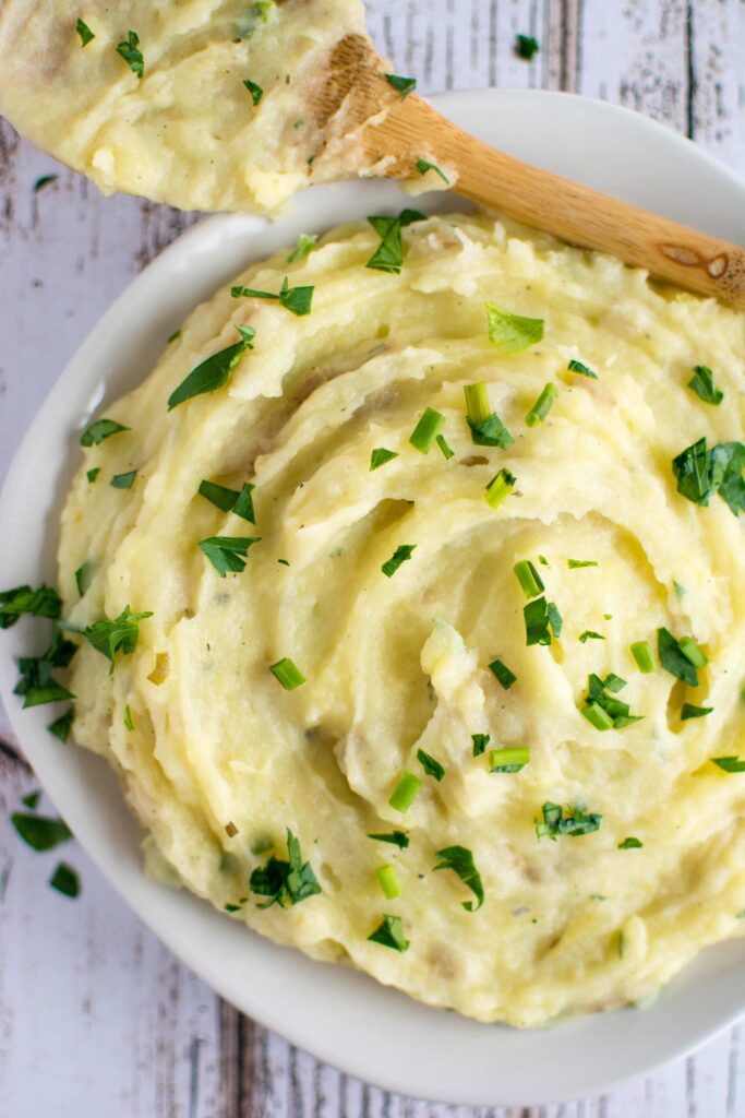 mashed potatoes in white bowl with wooden spoon