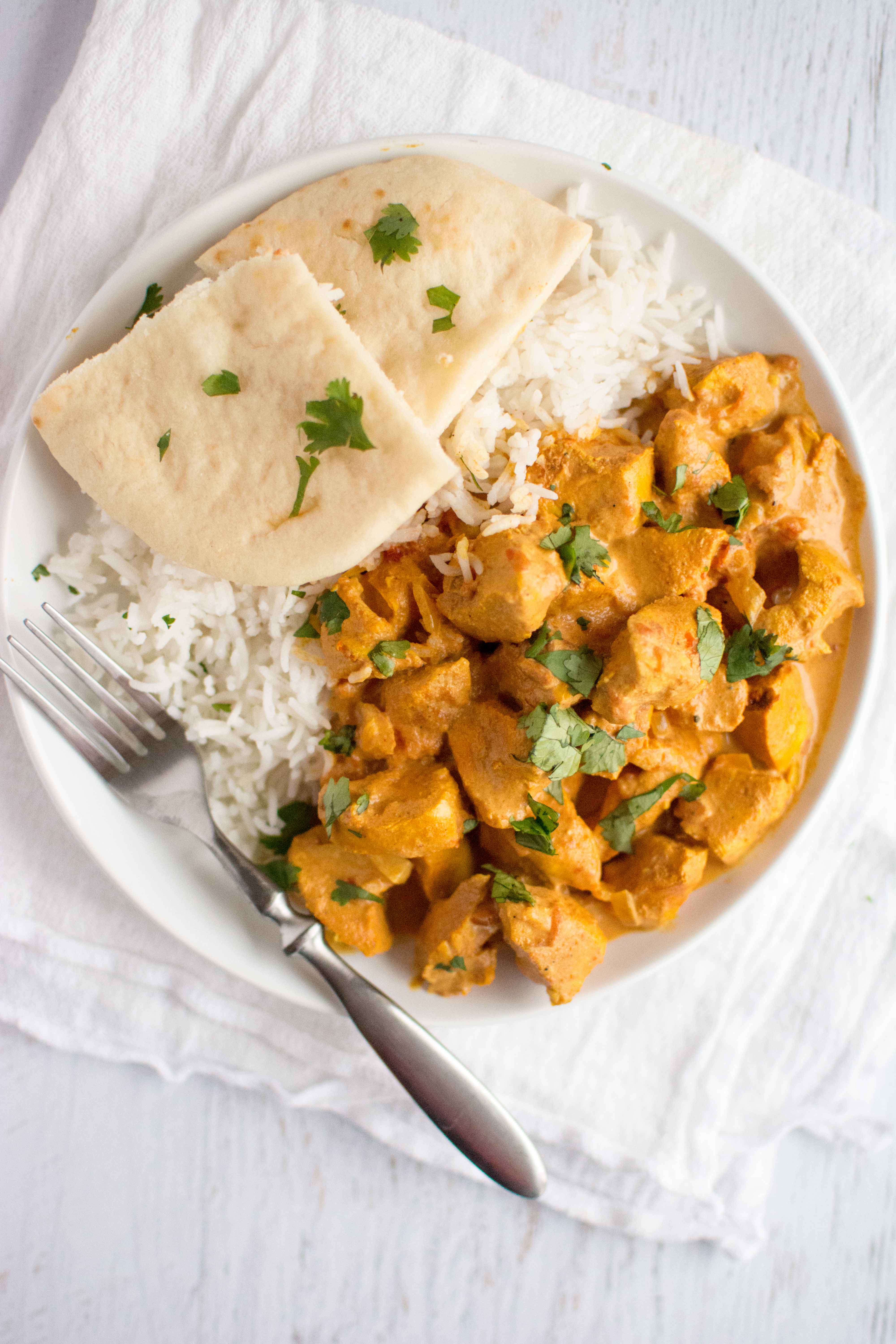 tikka masala, rice and naan in white plate with fork 