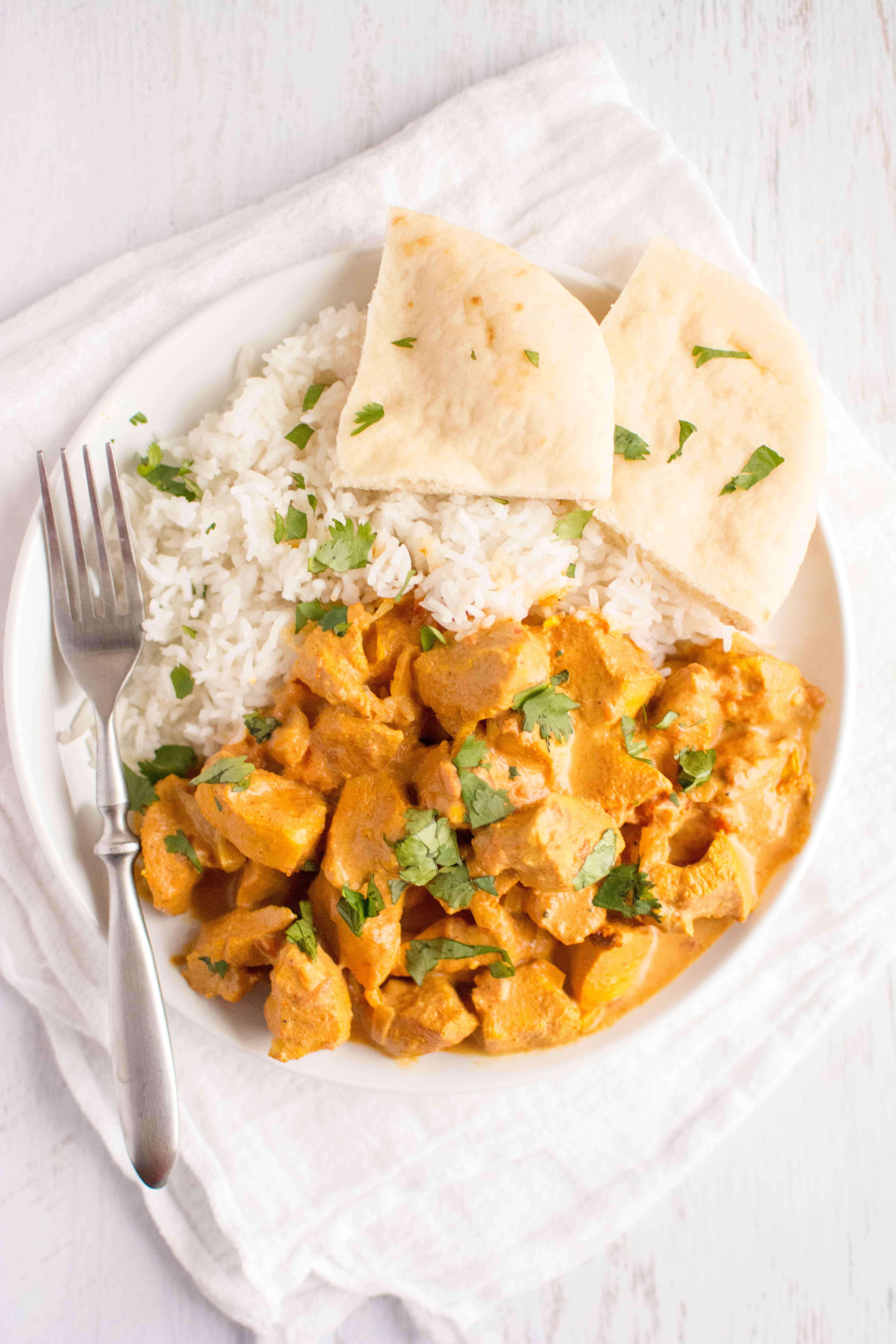 tikka masala, rice and naan in white plate with fork