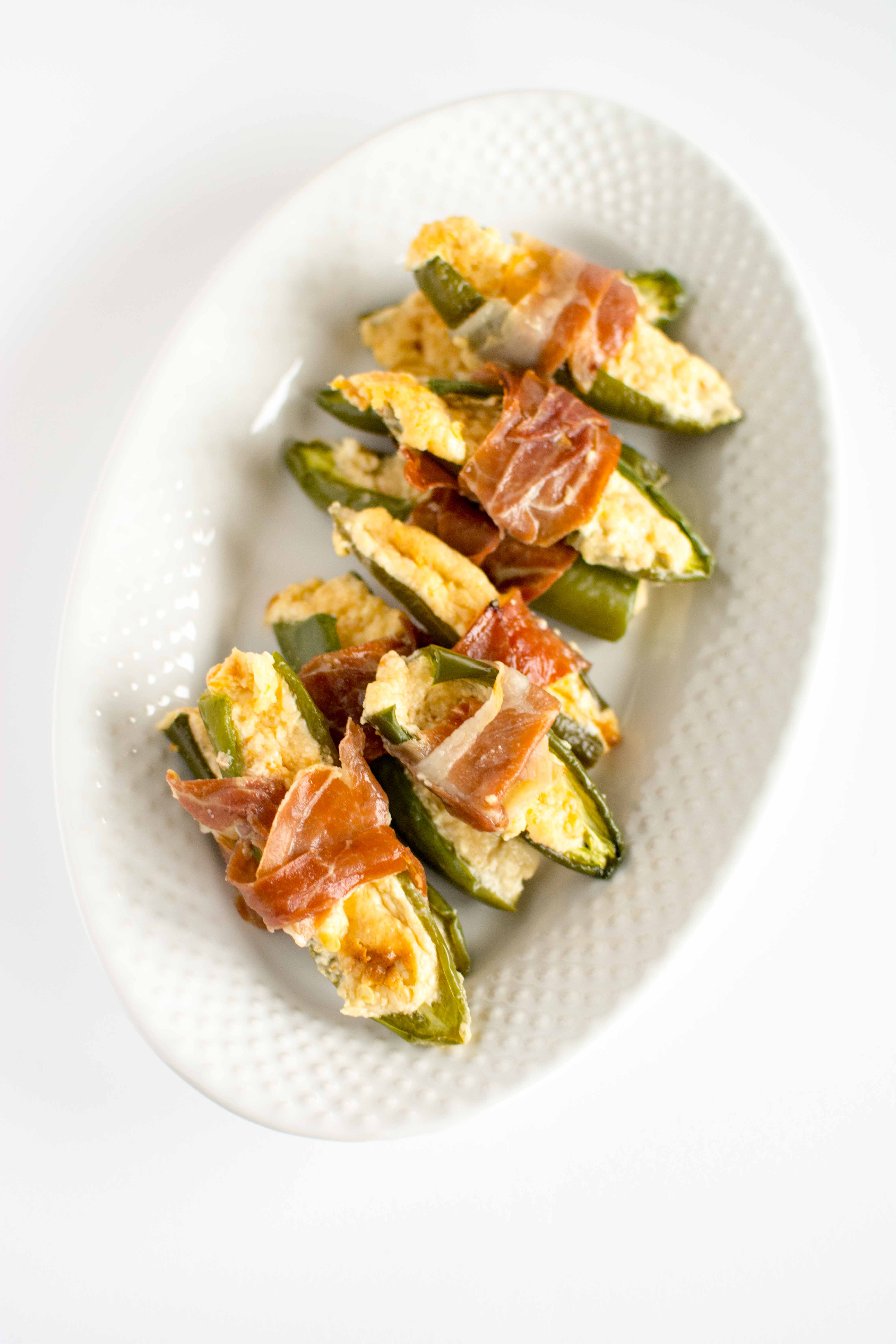 jalapeno poppers wrapped in proscuitto on white serving platter