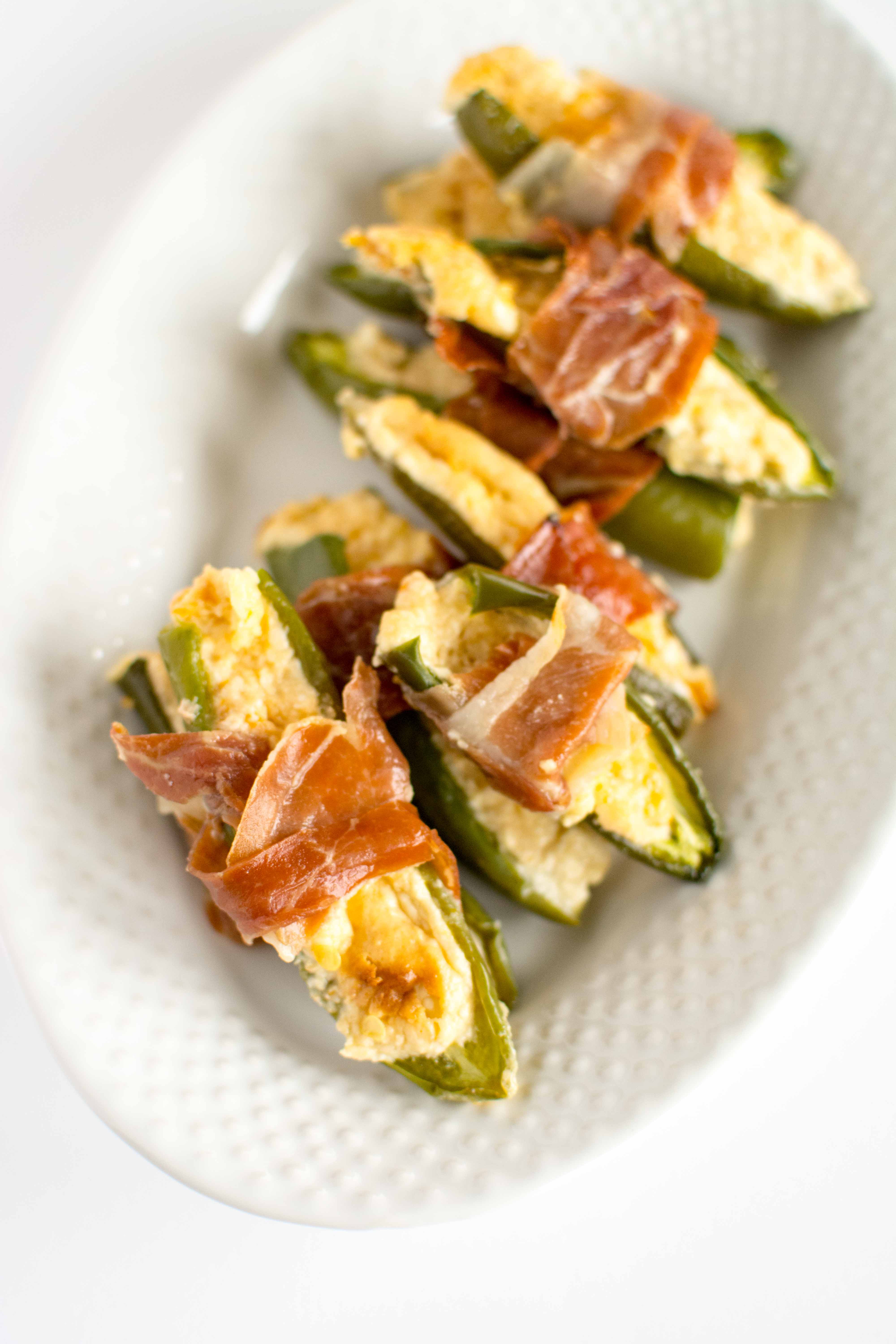 jalapeno poppers wrapped with proscuitto on white platter