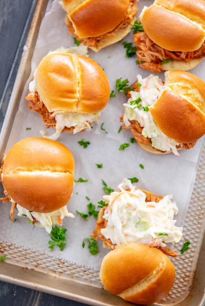 tray Slow Cooker BBQ Pulled Chicken sandwiches on Hawaiian slider bun topped with coleslaw