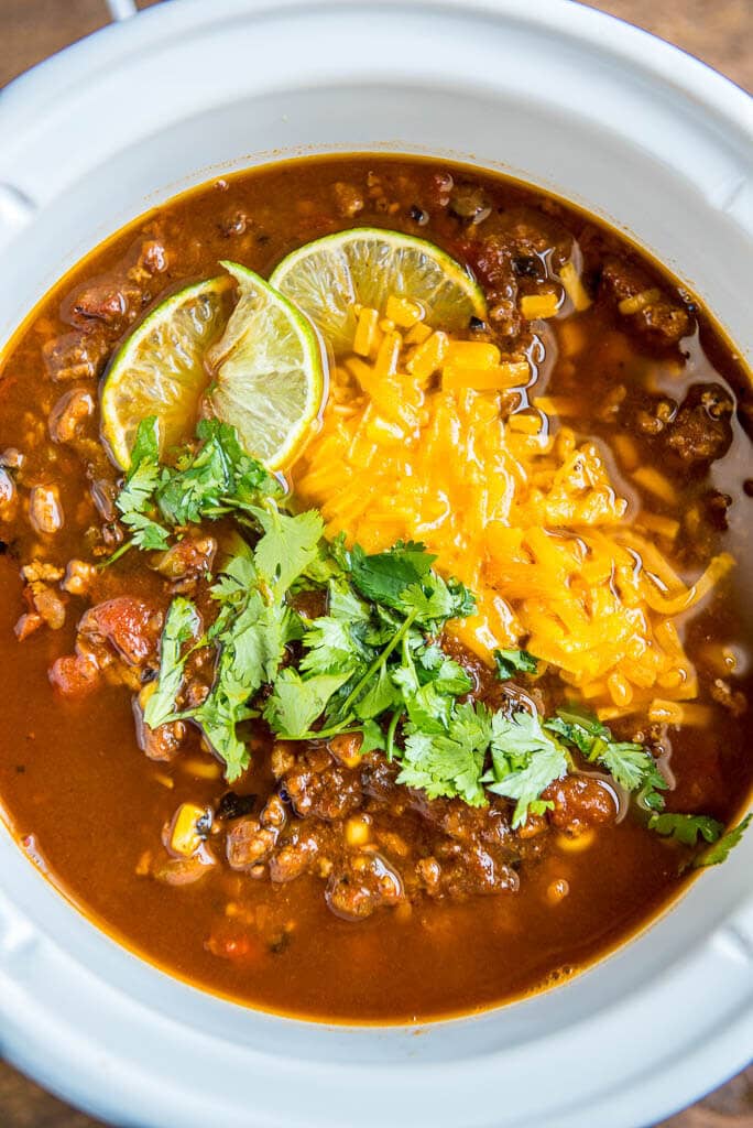 taco soup with cilantro, cheese and lime wedge in slow cooker